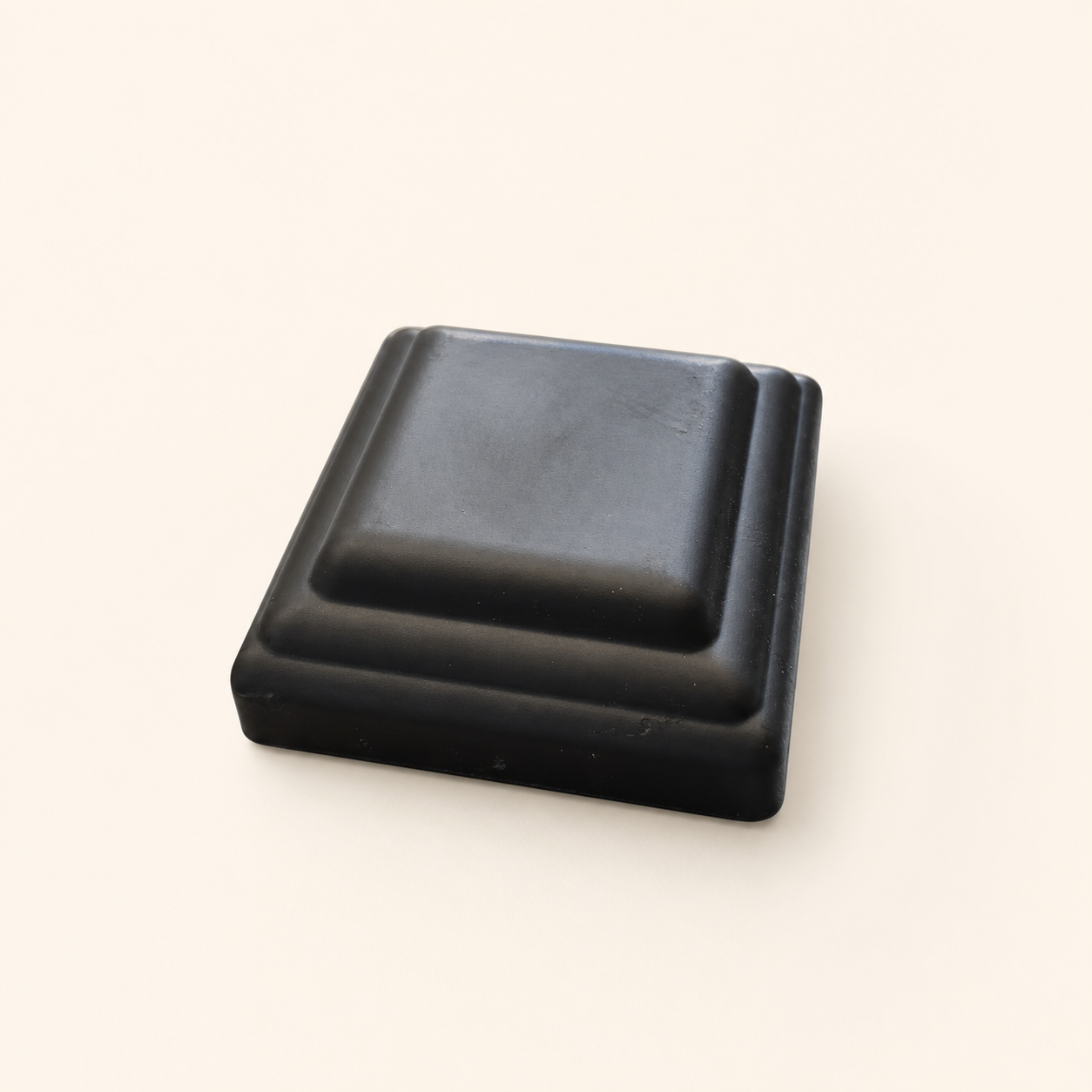 Black aluminum Compoxen fence post cap on a warm studio background